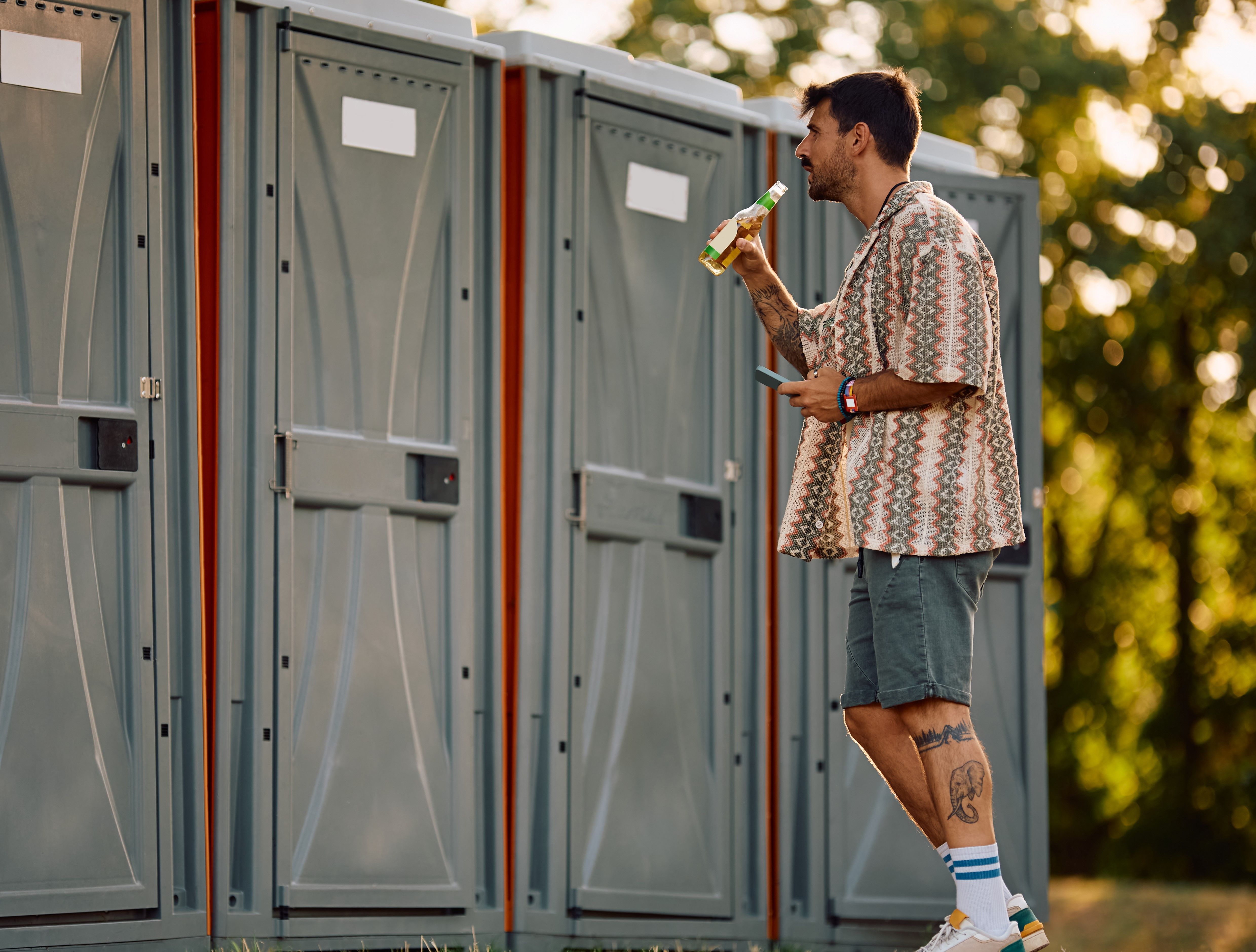 young-man-waiting-in-front-of-portable-toilet-duri